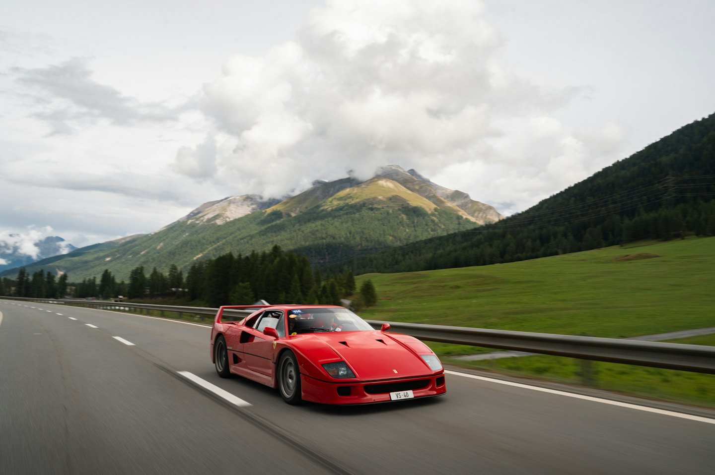 Red sports car driving along a winding mountain road.
