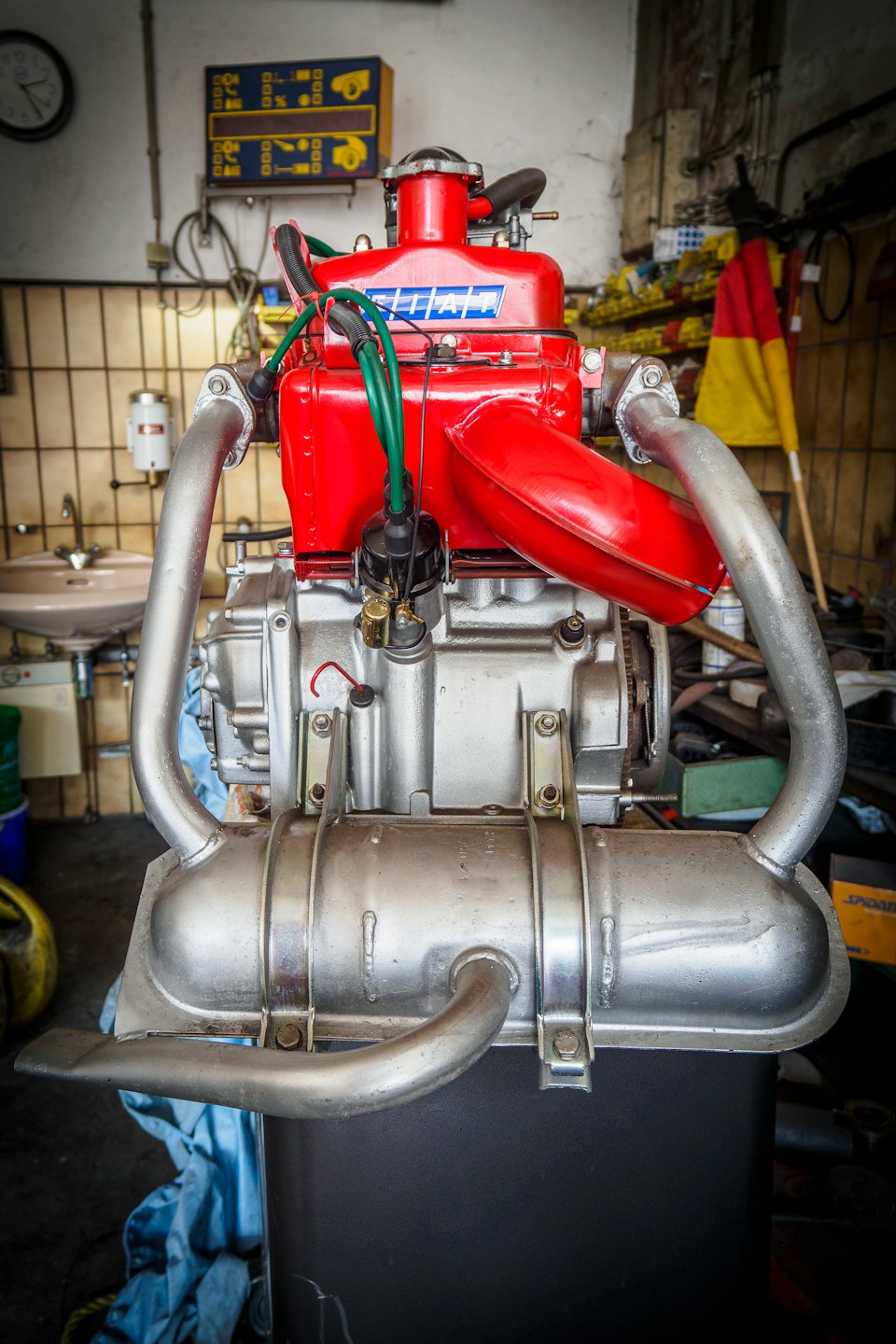 Restored vintage engine with red block displayed in a workshop.