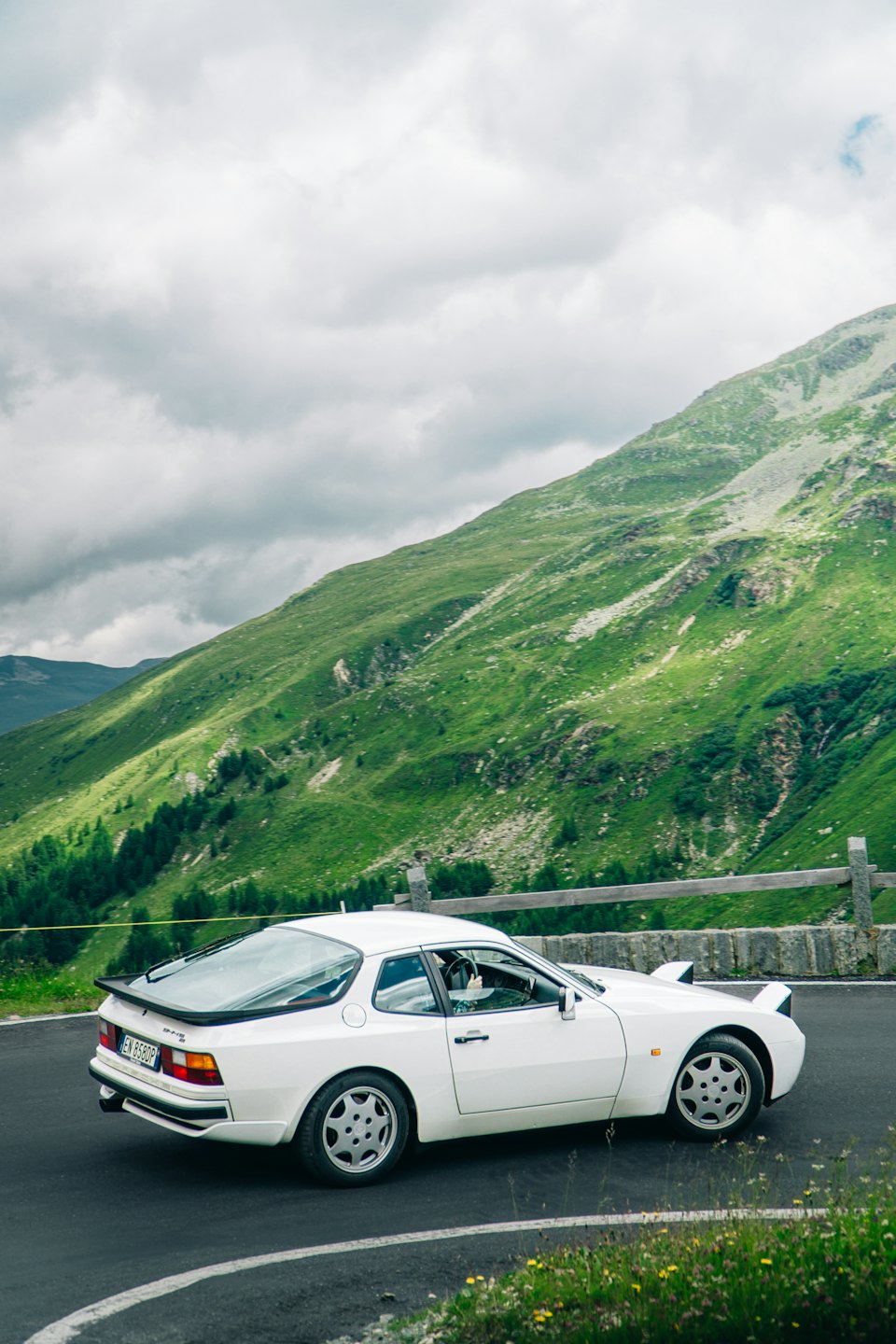 Vintage white sports car parked on a scenic mountain road.