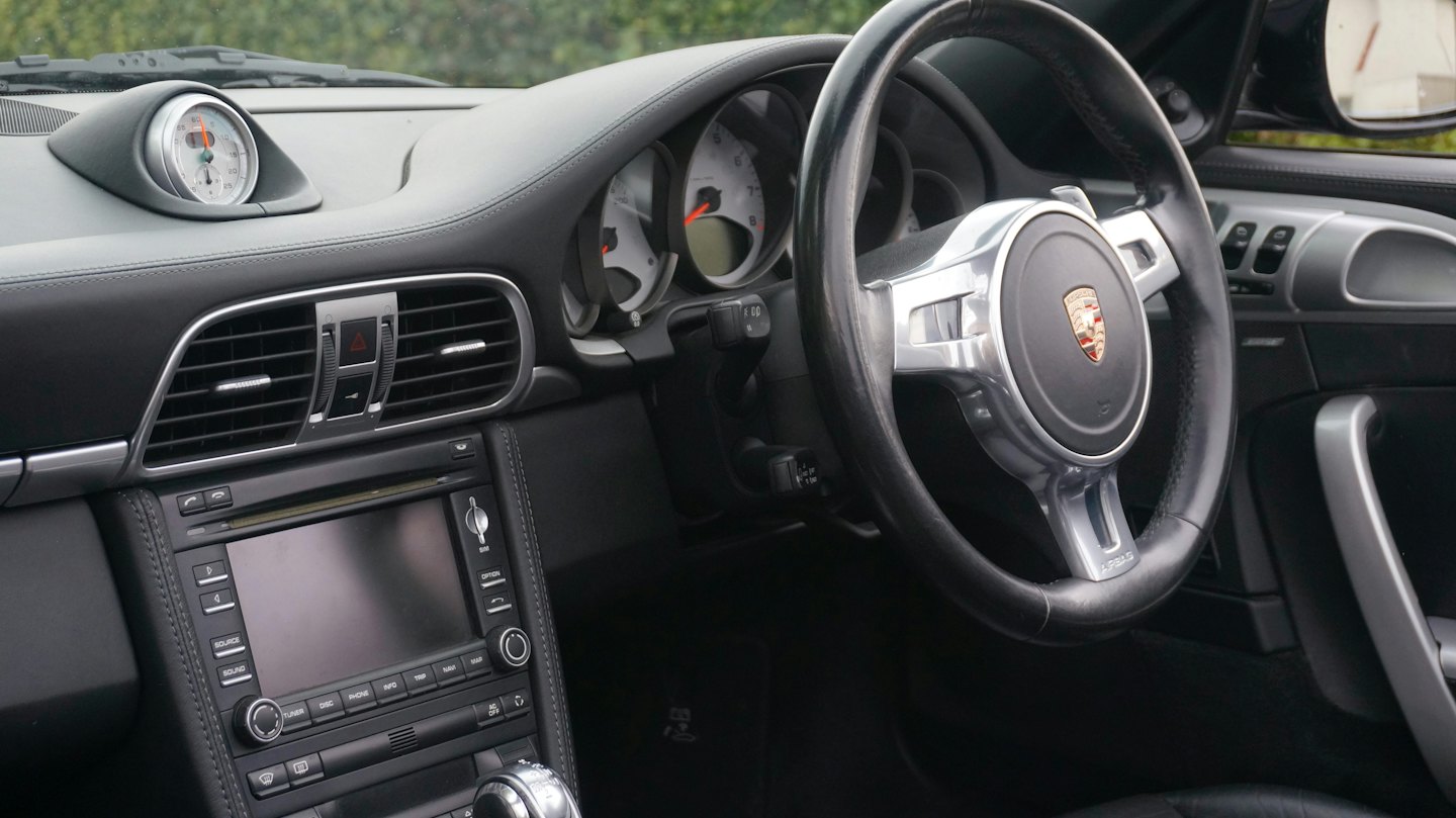 Luxury car dashboard featuring a leather steering wheel and chronometer.
