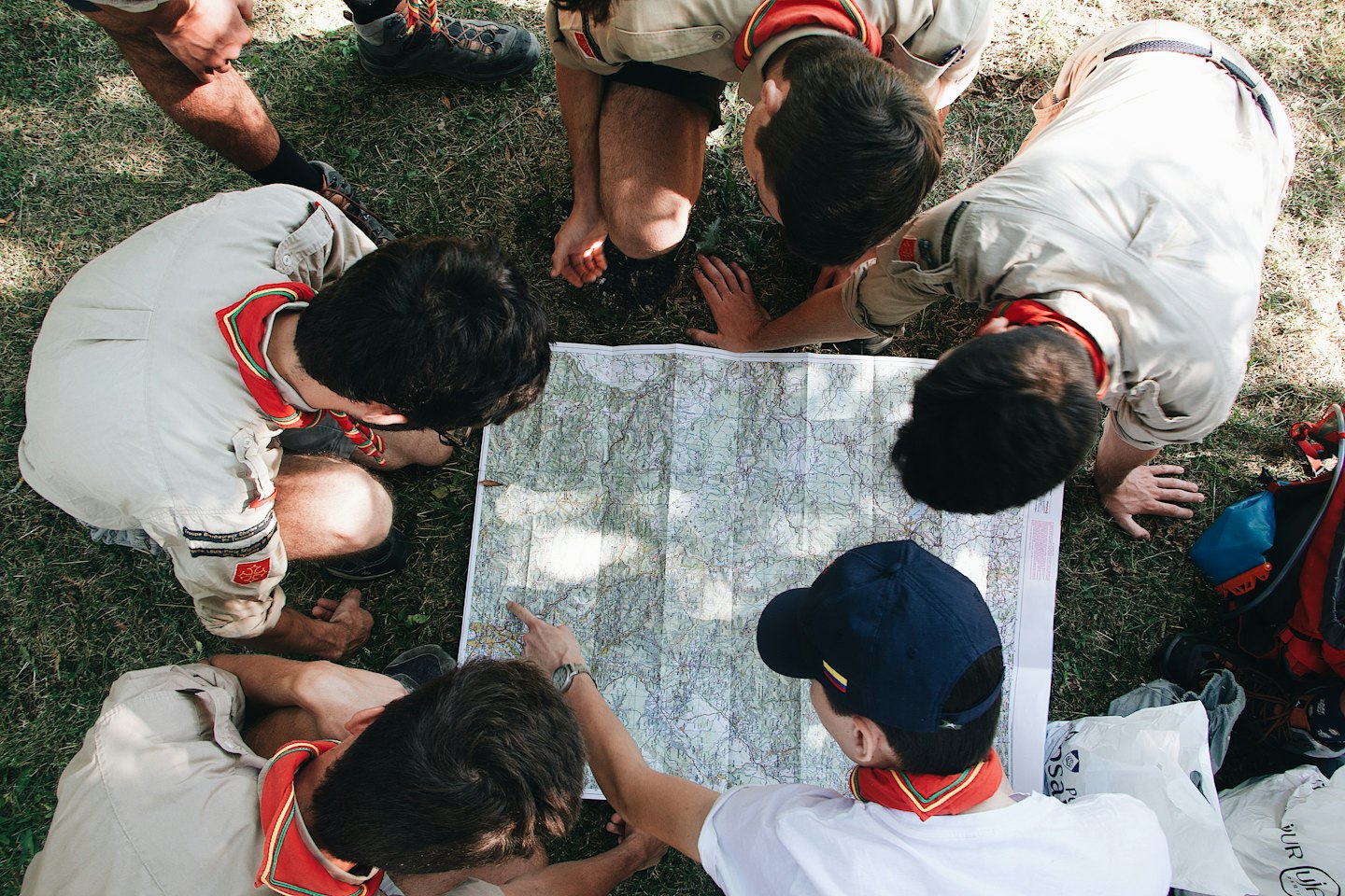 Scouts in uniform studying a map on the grass.